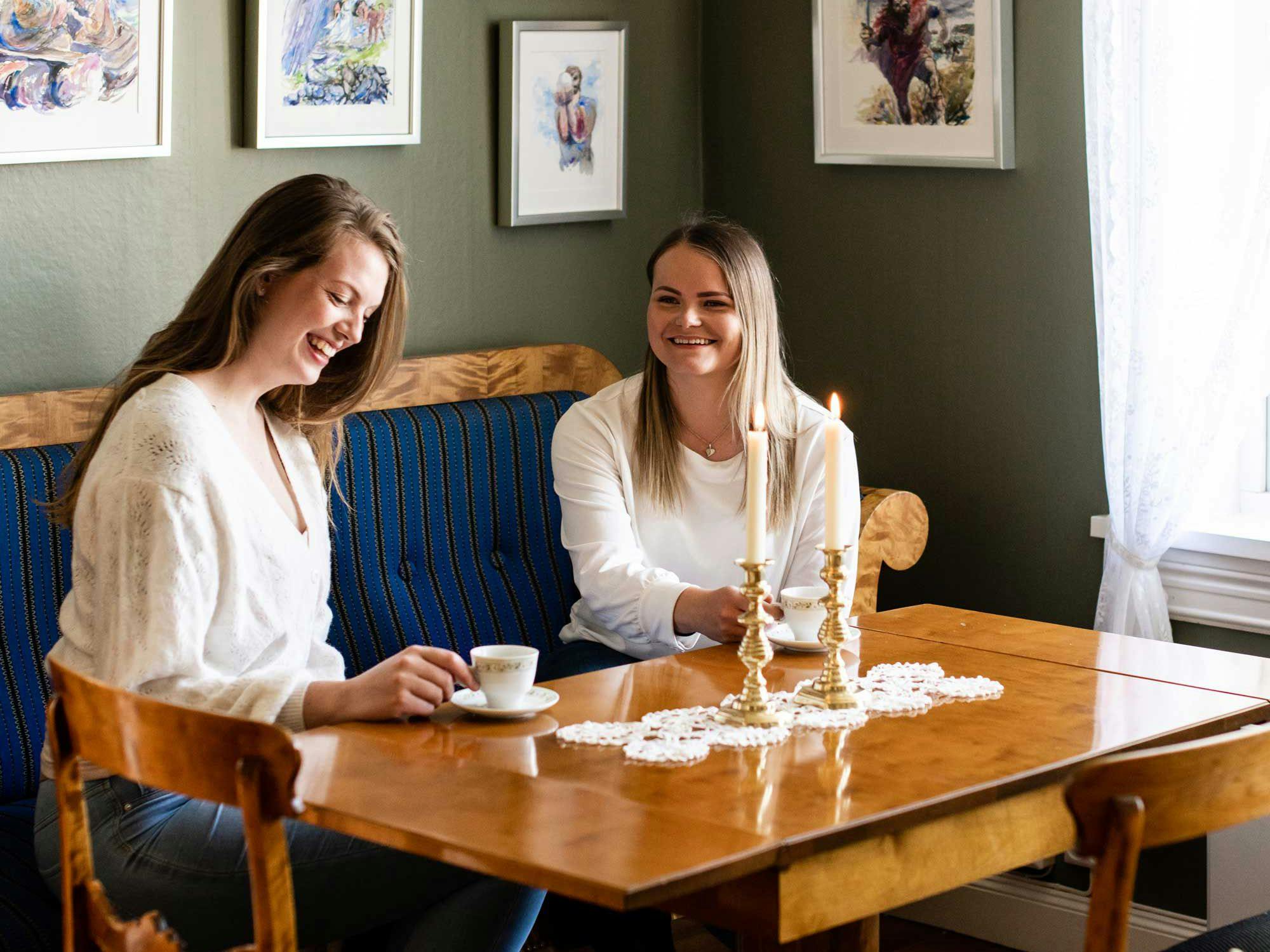 To jenter som drikker kaffe ved et bord.